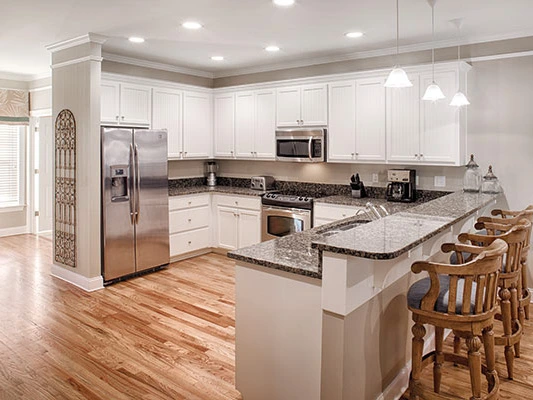 Open-concept kitchen with white cabinetry, granite countertops, and barstools, showing timeshare values over time.