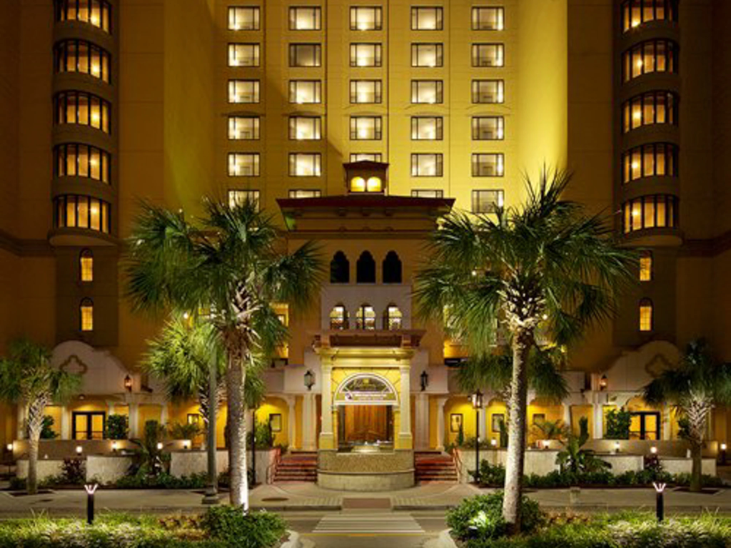 Evening entrance view of Anderson Ocean Club framed by lit palm trees and a grand symmetrical facade.