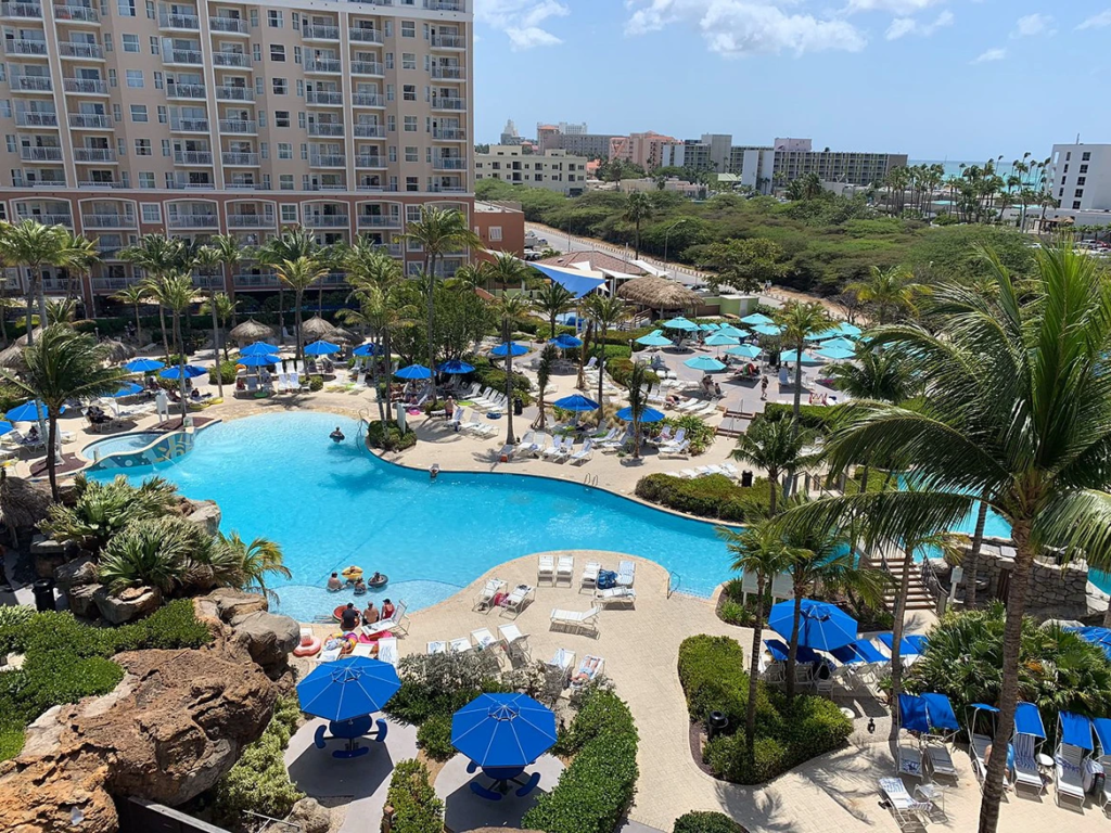 High-angle view of the expansive tropical swimming pool and sun loungers at Marriott's Aruba Surf Club.