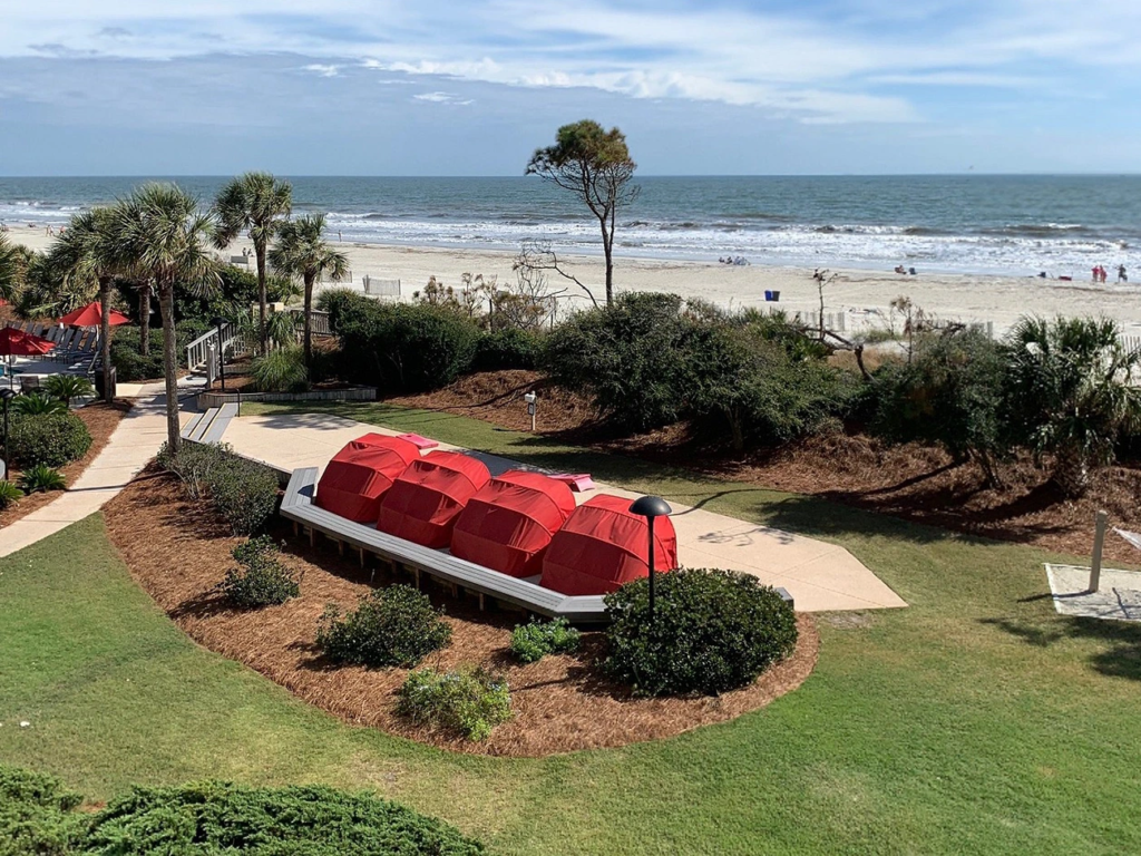 Red shaded loungers overlooking the sandy shoreline and ocean at Marriott's Monarch at Sea Pines.