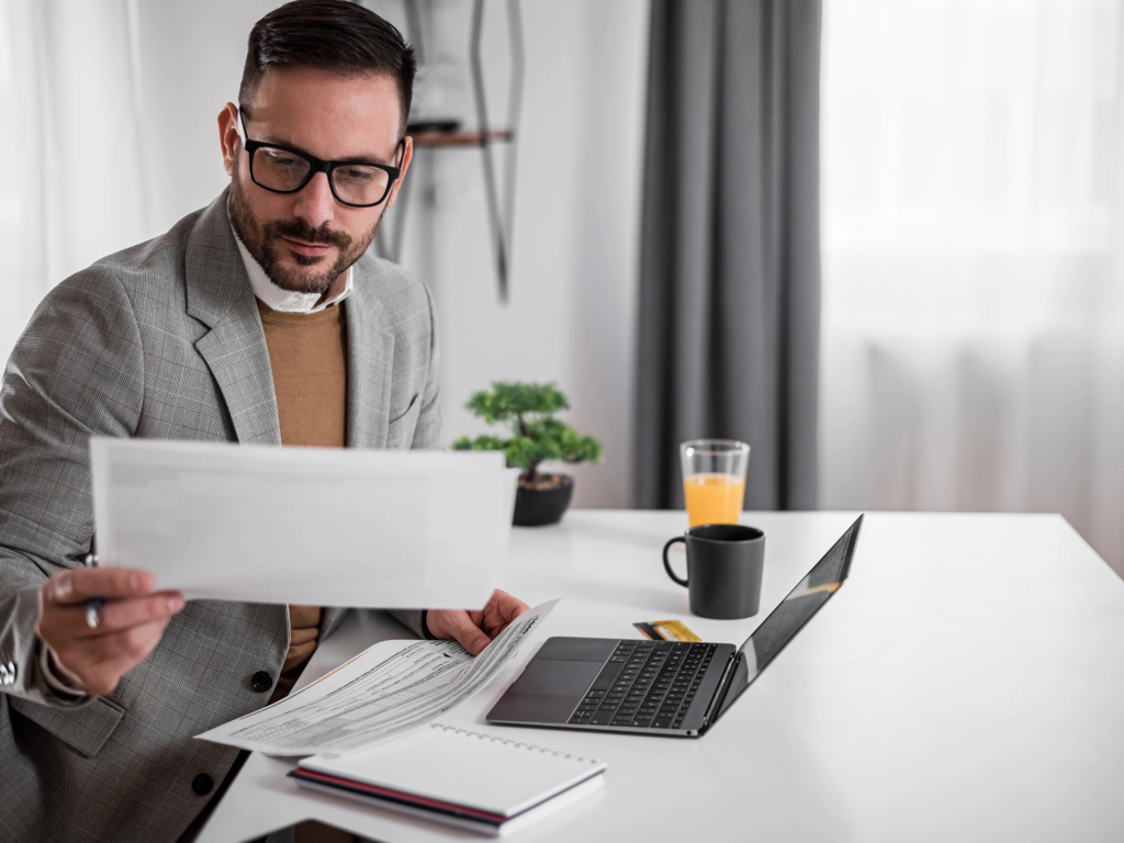 A professional consultant in a grey blazer reviewing vacation ownership contracts and documents at a bright desk.