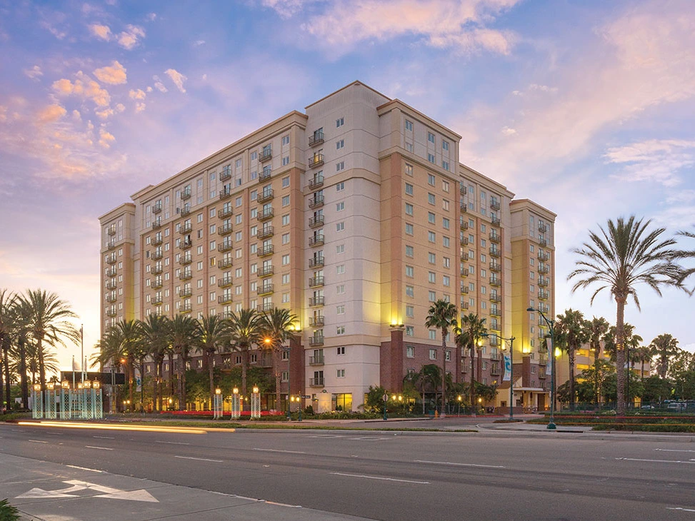Exterior view of the Anaheim resort building illuminated at dusk with palm trees.