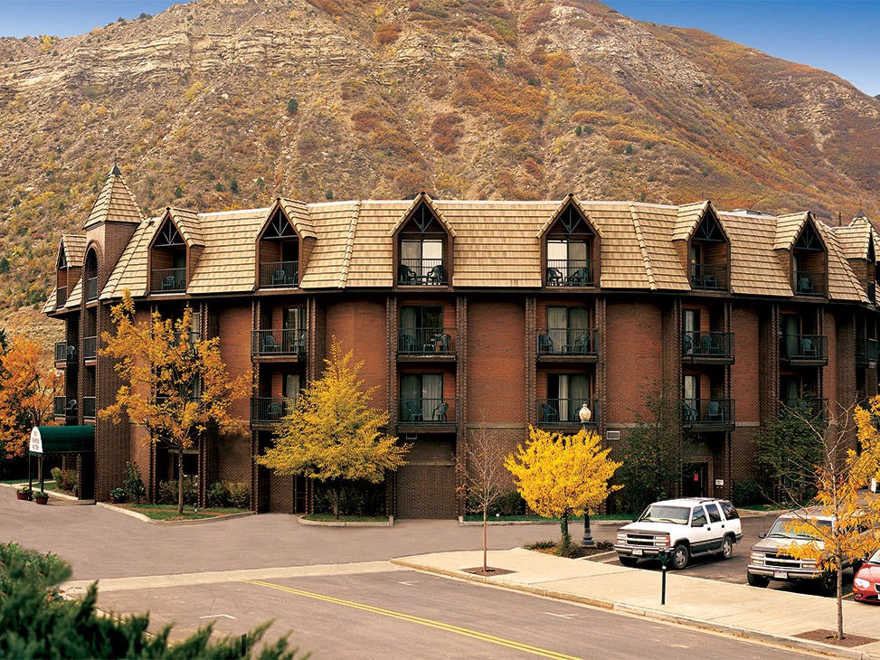 Sell Wyndham Points: a brick hotel with a mountain backdrop and colorful trees in autumn around it.