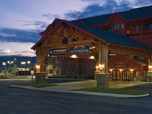 The entrance of Wyndham Wilderness Resort at night with a wooden canopy and bright lights.