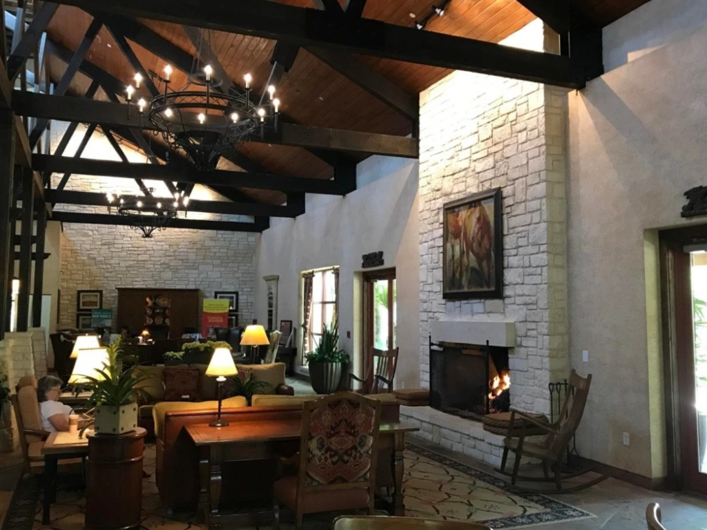 A cozy lobby at Wild Oak Ranch, with high wooden beams, stone fireplace, and comfortable seating.