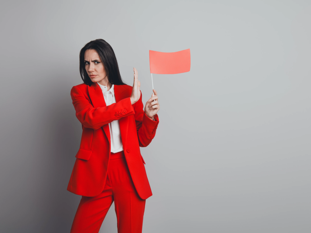 A woman in a red suit holding a warning flag to represent common timeshare resale scams and red flags.