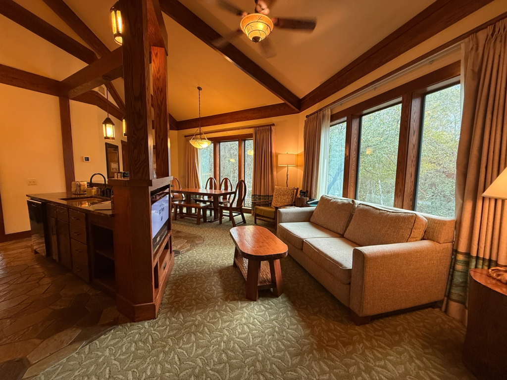 Cozy living area with a sofa, coffee table, and dining table near large windows.