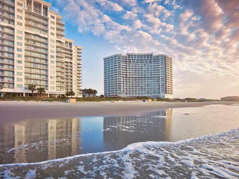 Beachfront view of the Club Wyndham SeaWatch resort towers by the ocean.