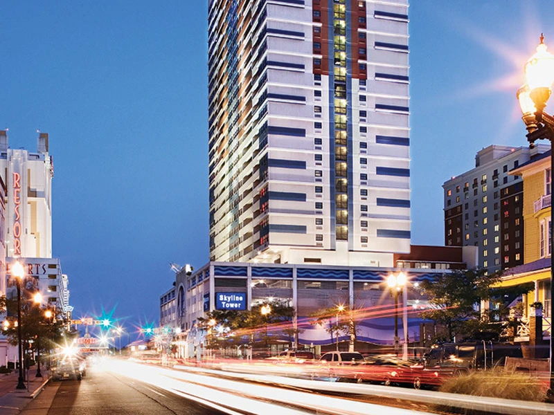 Sell Wyndham Points – a tall building named Skyline Tower illuminated at dusk, with busy streets and car lights below.
