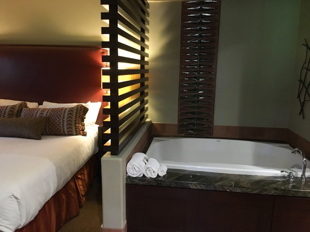A cozy room at Hyatt Pinion Pointe, with a large bed, decorative pillows, and an elegant bathtub nearby.