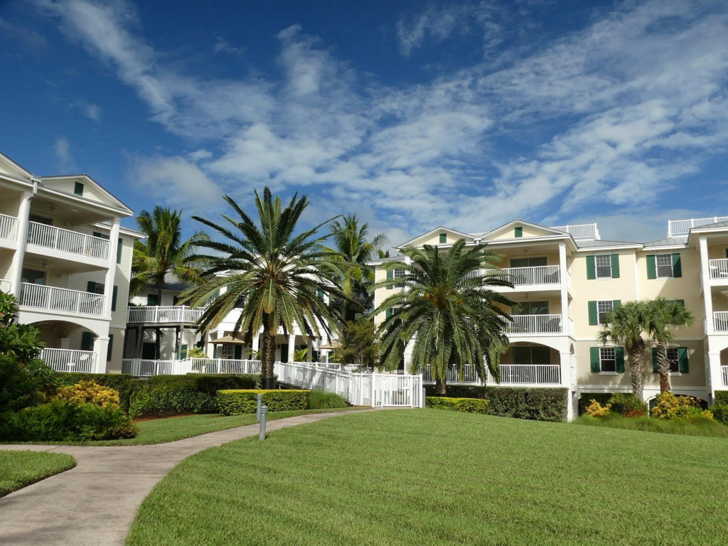 A sunny view of Windward Pointe with palm trees and green grass.