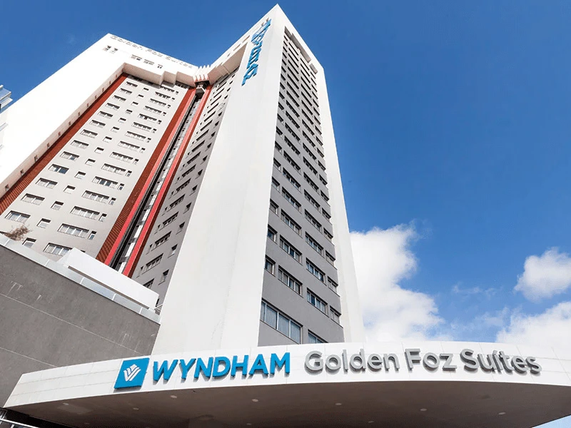 Sell Wyndham Points at Wyndham Golden Foz Suites hotel building with a modern design against a blue sky.