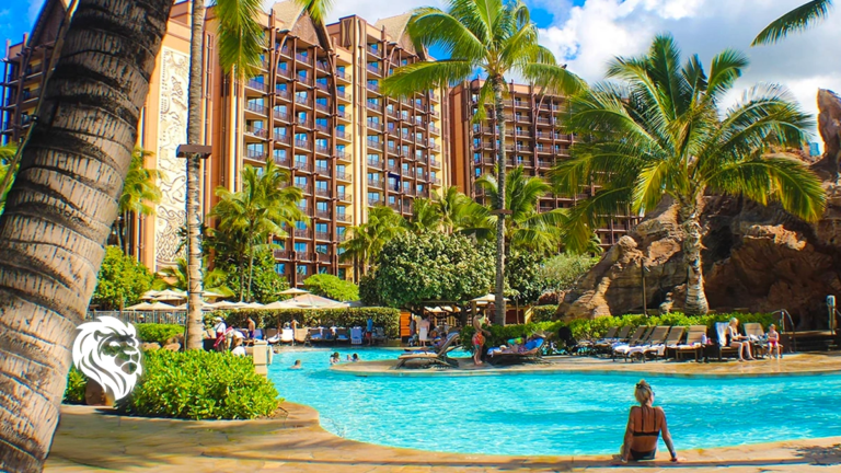 Sunny outdoor swimming pool surrounded by tropical palm trees and tall resort towers at Aulani in Hawaii.