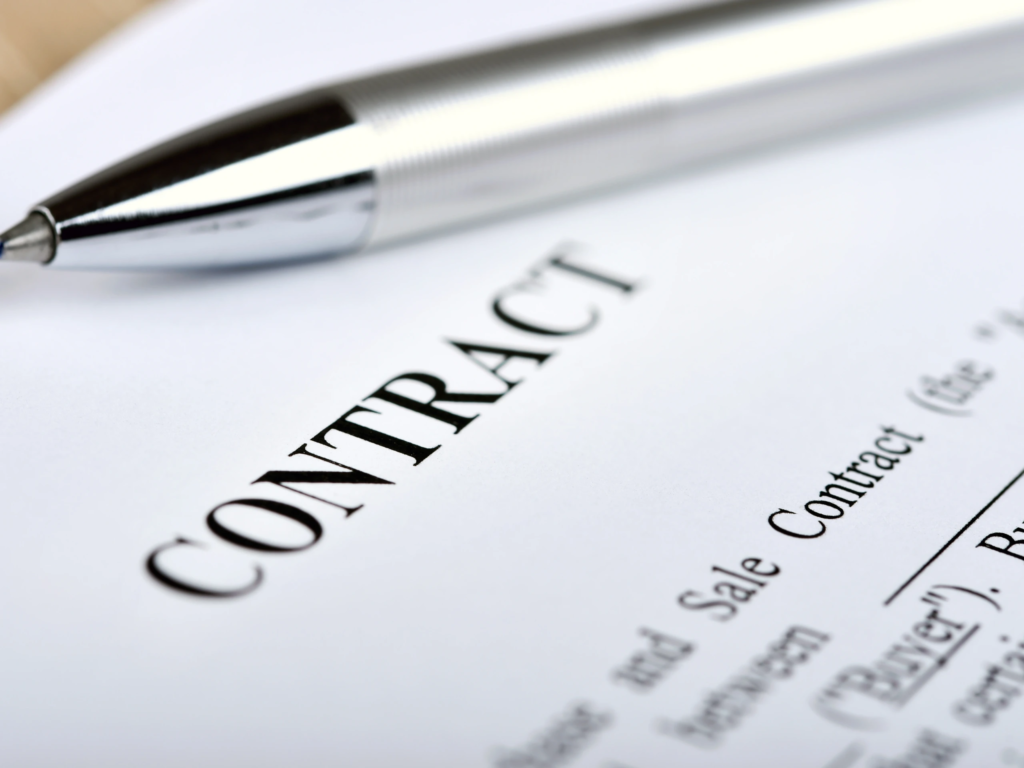 Close-up of a printed Contract document with a silver pen resting on top of the paperwork.