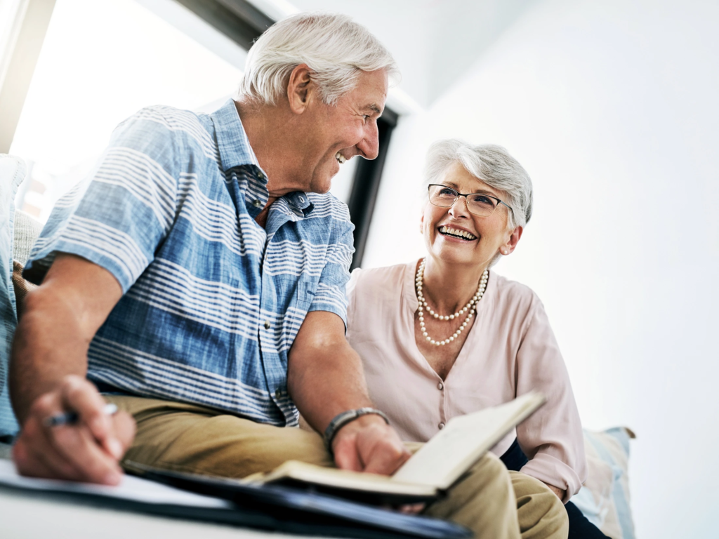 A happy retired couple smiling while reviewing paperwork regarding timeshare cancellation vs resale.