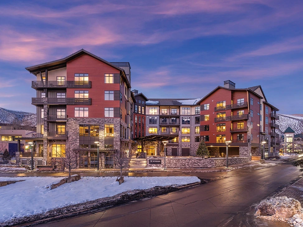 The exterior of Club Wyndham Avon mountain resort during winter at twilight.