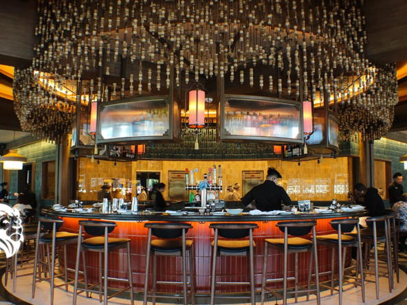 A central round bar with glowing red paneling and a hanging beaded canopy inside Din Tai Fung.