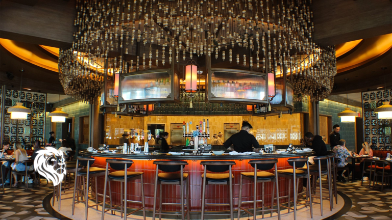 A central round bar with glowing red paneling and a hanging beaded canopy inside Din Tai Fung.
