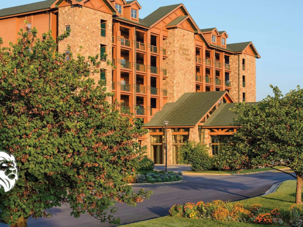 Exterior view of the rustic Westgate Branson Woods resort building featuring stone siding, trees, and a driveway.