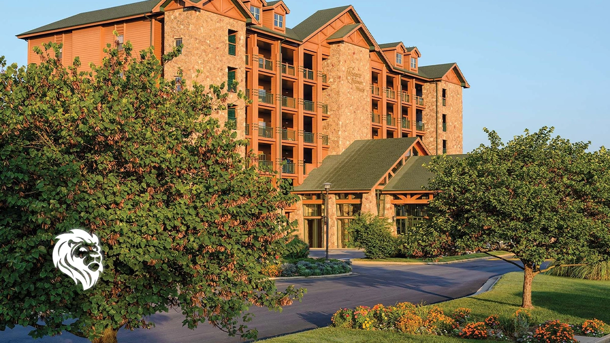 Exterior view of the rustic Westgate Branson Woods resort building featuring stone siding, trees, and a driveway.