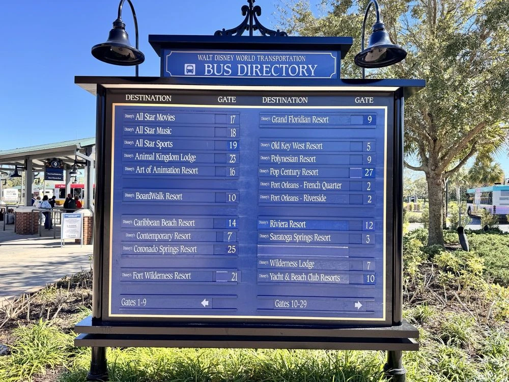 A blue Walt Disney World bus directory sign listing resort destinations and their assigned boarding gate numbers.