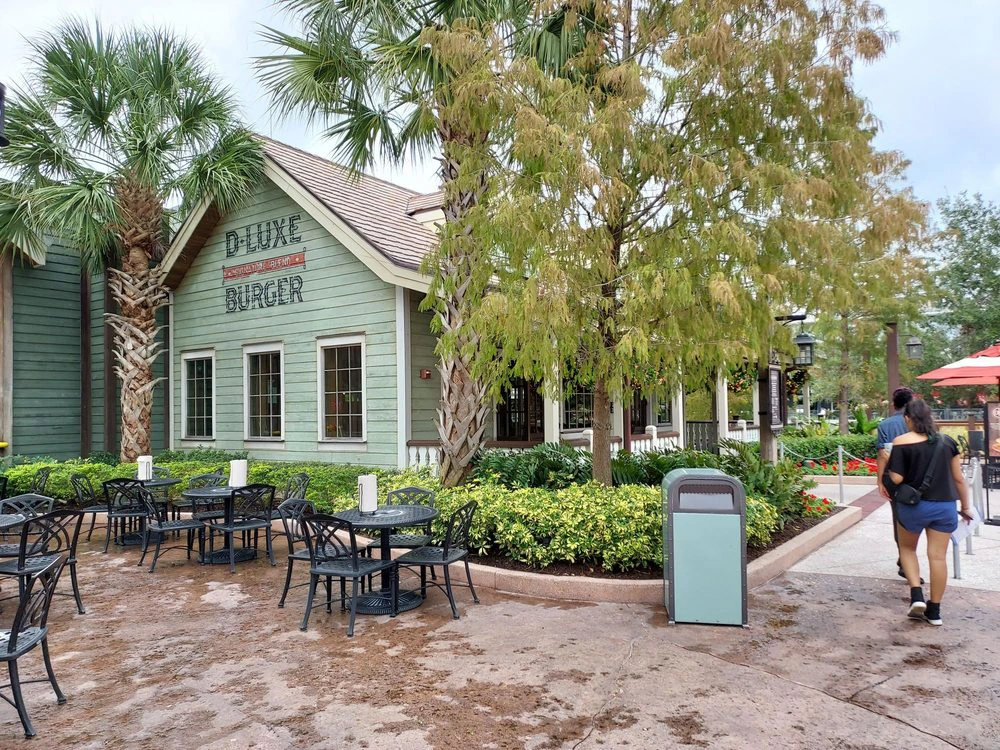 The rustic green exterior and empty outdoor seating patio of D-Luxe Burger restaurant at Disney Springs.