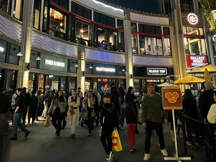 Evening crowds walking past illuminated storefronts to dine at the Best Downtown Disney Restaurants.