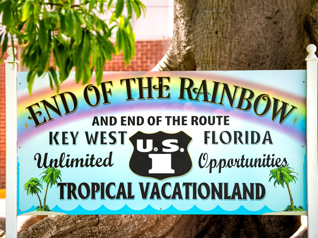 Colorful roadside welcome sign reading End of the Rainbow in Key West, Florida.