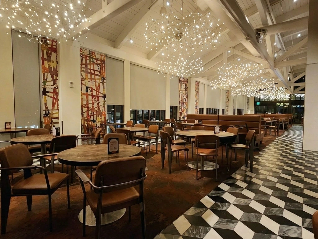 Spacious dining room interior with modern starburst lighting fixtures and rustic tables at Naples Ristorante e Bar.