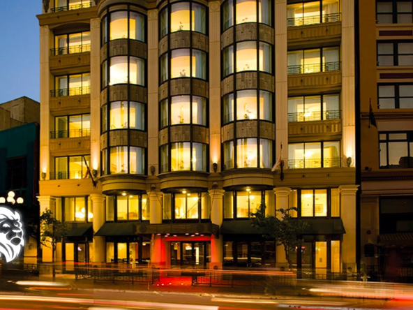 Illuminated exterior of Club Wyndham Harbour Lights at night featuring rounded bay windows and car light trails.
