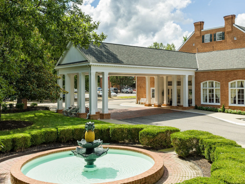 Brick colonial-style entrance with a white portico and pineapple fountain at Westgate Historic Williamsburg.
