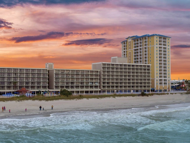 Westgate Myrtle Beach Oceanfront Resort along a sandy beach under a vibrant sunset sky, ideal for labor day travel.