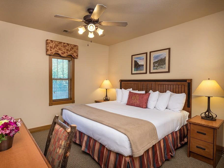 Cozy bedroom at Westgate Branson Woods Resort featuring a king bed and rustic log chair.