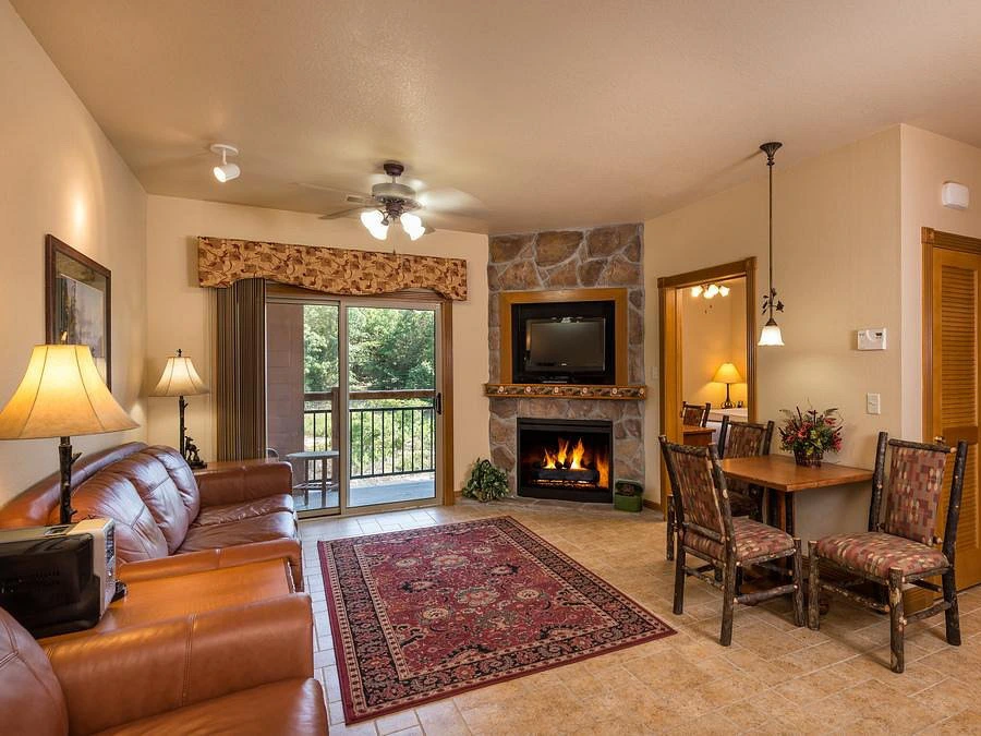 Warm living room at Westgate Branson Woods Resort with leather sofas and a stone fireplace.