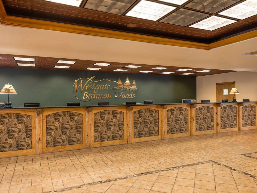 A long wooden check-in counter inside a rustic resort lobby with a dark green accent wall.