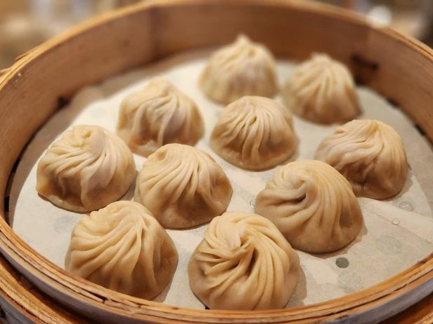 Steamed soup dumplings in a round bamboo steamer basket, popular fare at the Best Downtown Disney Restaurants.