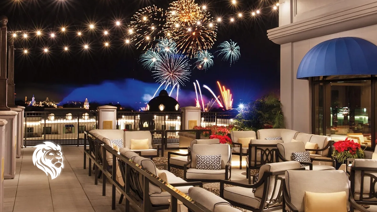 Rooftop terrace with lounge seating and string lights overlooking a colorful fireworks display at night.