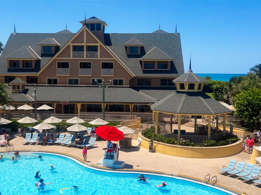 Aerial view of the pool at Disney's Vero Beach Resort with lounge chairs, umbrellas, and a lifeguard stand.