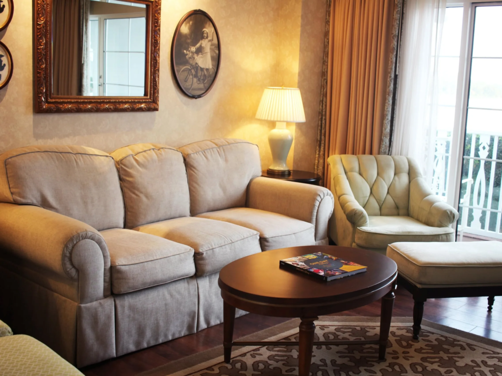 Disney Vacation Club villa living room with a beige sofa, tufted armchair, and sliding glass doors.
