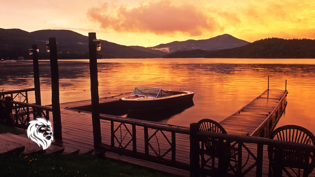 Wooden dock and moored boat at sunset on a calm lake, perfect for romantic getaways in upstate NY.