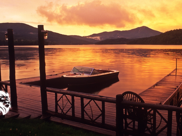 Wooden dock and moored boat at sunset on a calm lake, perfect for romantic getaways in upstate NY.