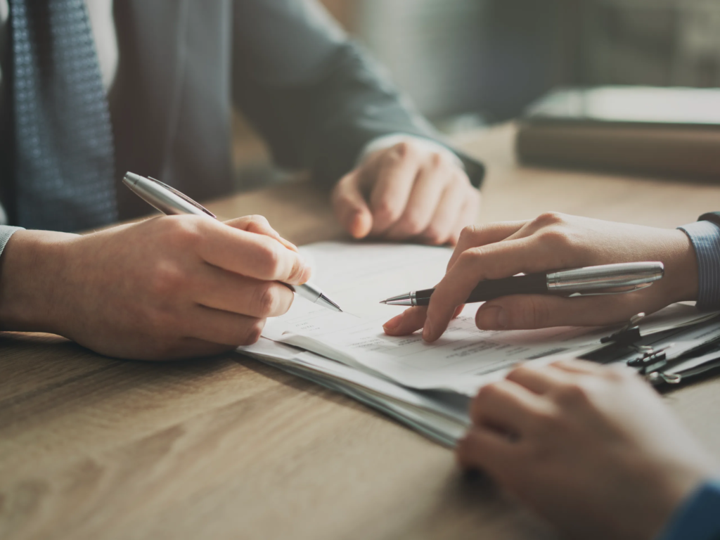 Two people signing documents at a desk, learning how to cancel my timeshares boca raton with legal paperwork.